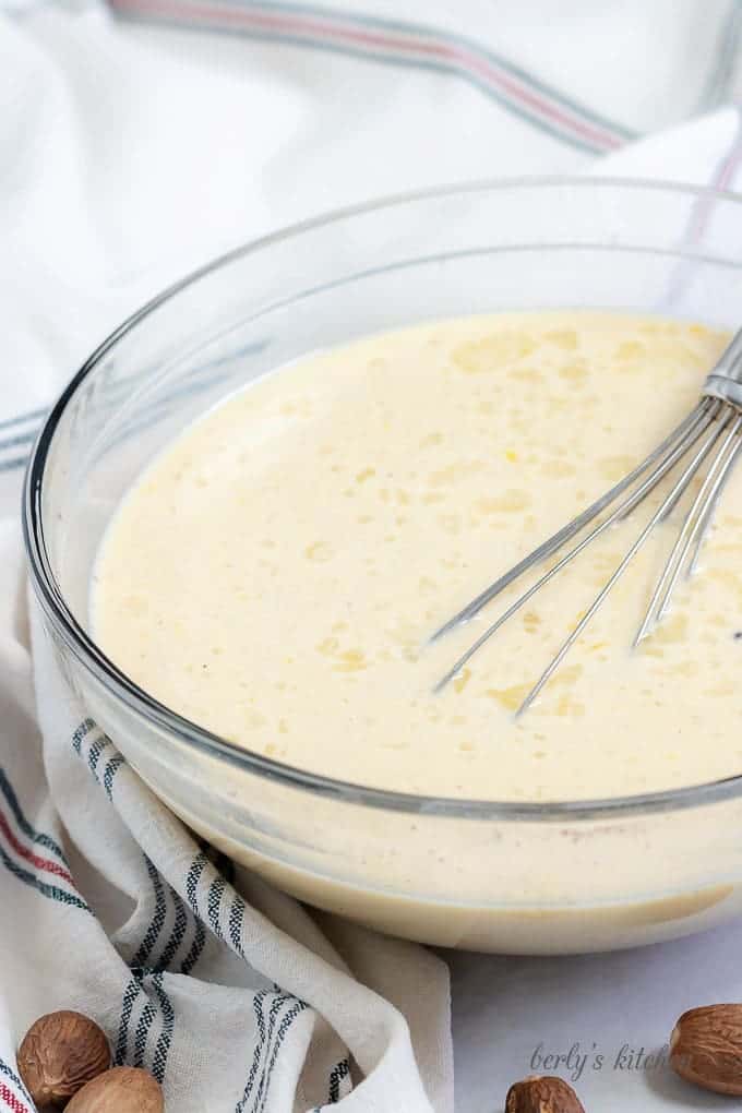The eggs, sugar, and other ingredients whisked together in a large glass mixing bowl.