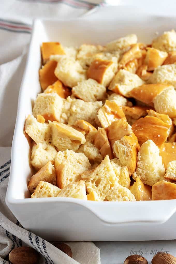 The day old bread has been ripped apart and placed into a large casserole dish.