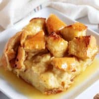 A close-up view of the bread pudding on a square plate accented with fresh nutmeg.