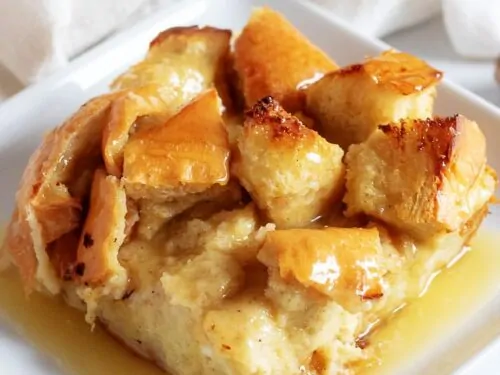 A close-up view of the bread pudding on a square plate accented with fresh nutmeg.