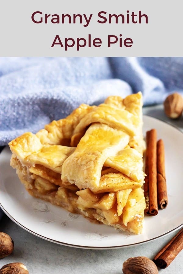 A slice of the finished granny smith apple pie served on a white plate with a cinnamon stick.