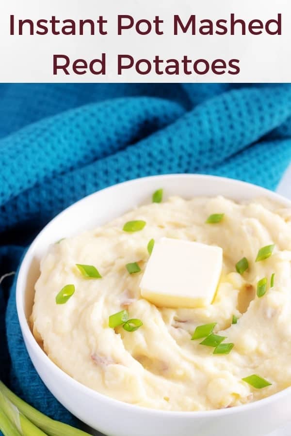 A large picture of the red mashed potatoes in a bowl topped with a pat of butter and sliced green onions.