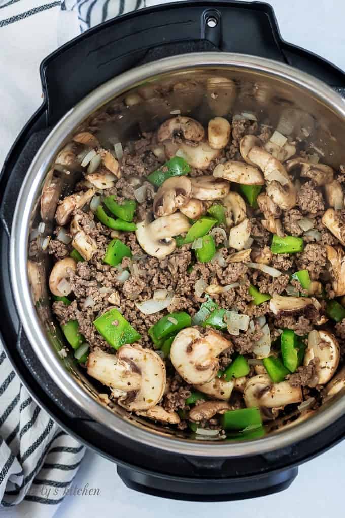 Top down view of cooked ground beef, mushrooms, onions, and green peppers in the instant pot.