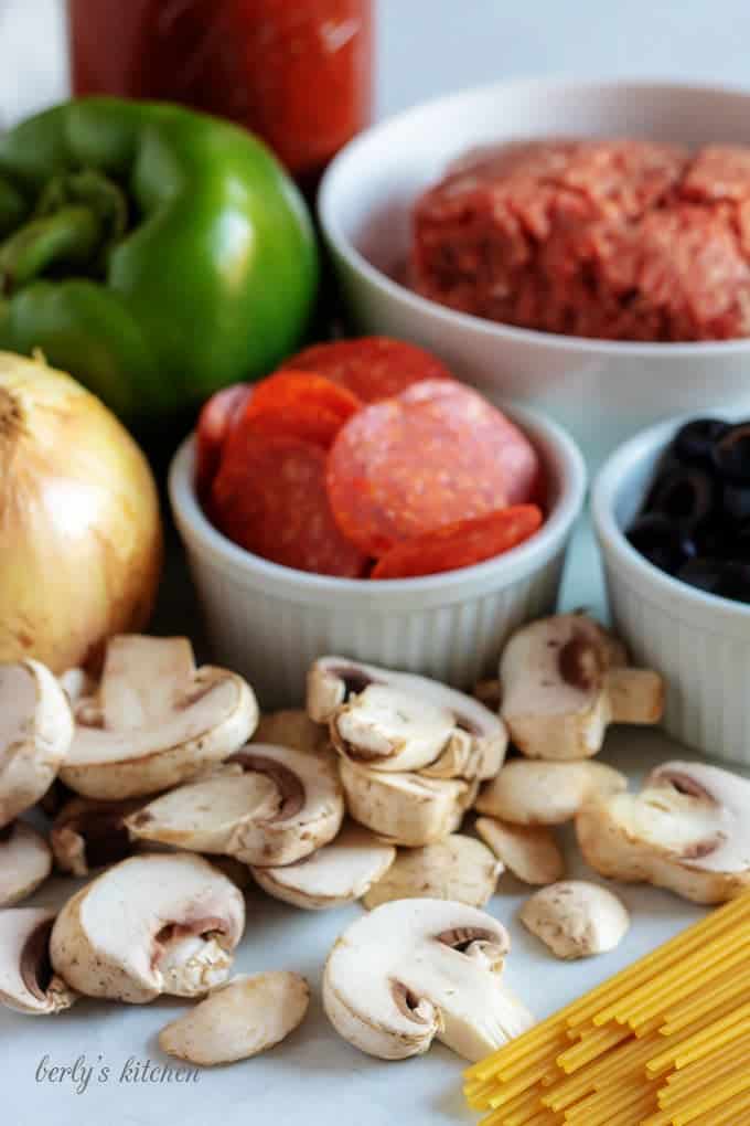 Pasta sauce, green pepper, pepperonis, onion, mushrooms, beef, olives, and pasta noodles used for Instant Pot Supreme Pizza Pasta.