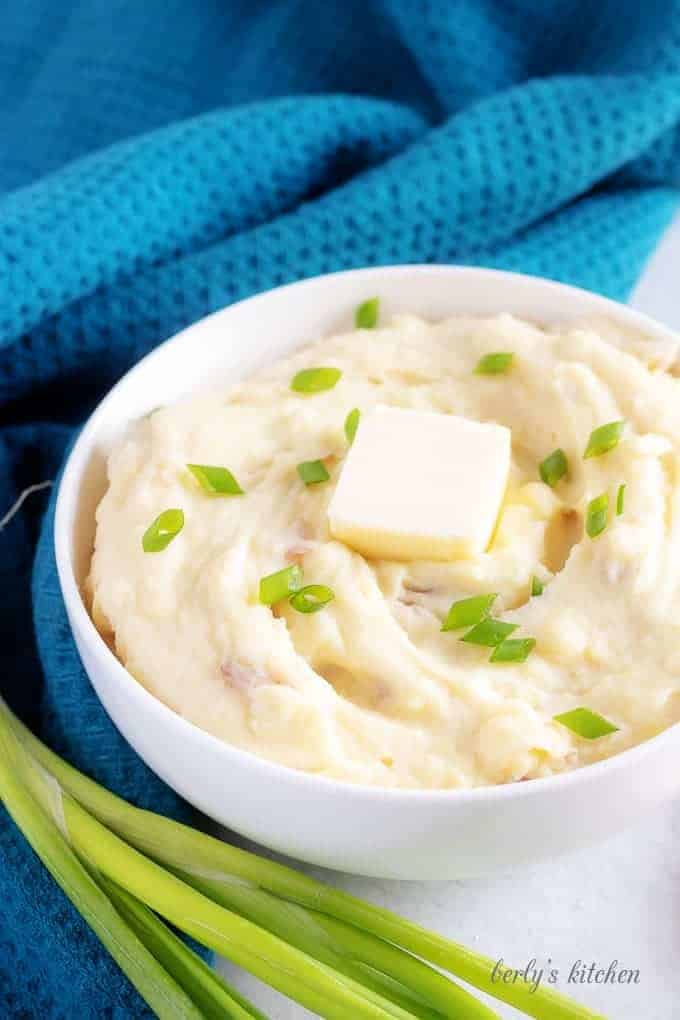 The final photo of the finished mashed red potatoes in a white serving bowl accented with a blue towel.