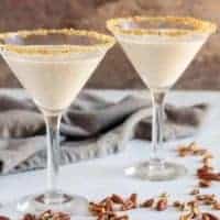 Two pecan pie martinis in martini glasses, rimmed with brown sugar and pecans.