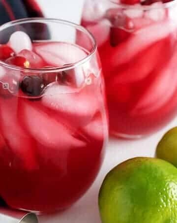 Two stemless wine glasses filled with our vodka cranberry cocktail garnished with fresh cranberries.