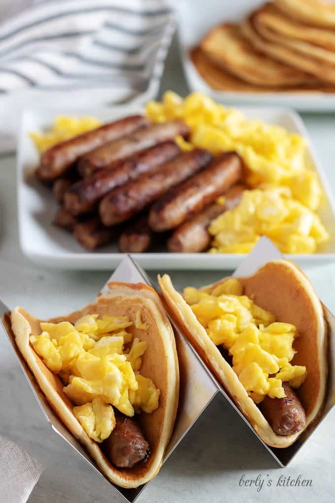 Two breakfast tacos, sitting on metal holders, ready to be served.