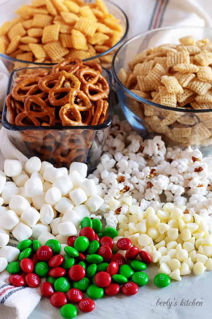 Pretzels, marshmallows, corn chex, rice chex, m&ms, popcorn, and white chocolate chips used for christmas chex mix.