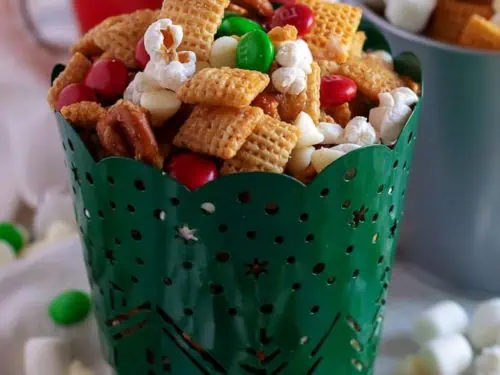 Christmas chex mix in red, green, and silver tins.