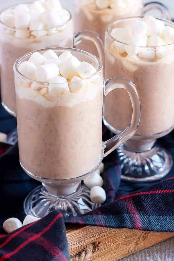 4 mugs of instant pot hot cocoa topped with marshmallows.