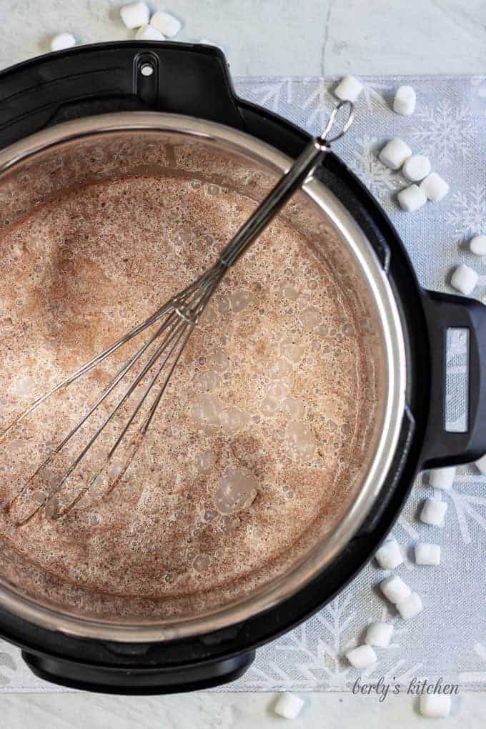 Top down view of instant pot hot cocoa in the instant pot with a whisk.