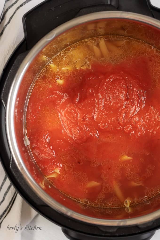 Top down view of the penne with vodka sauce recipe in the instant pot showing the tomato puree on top of the penne noodles and water.