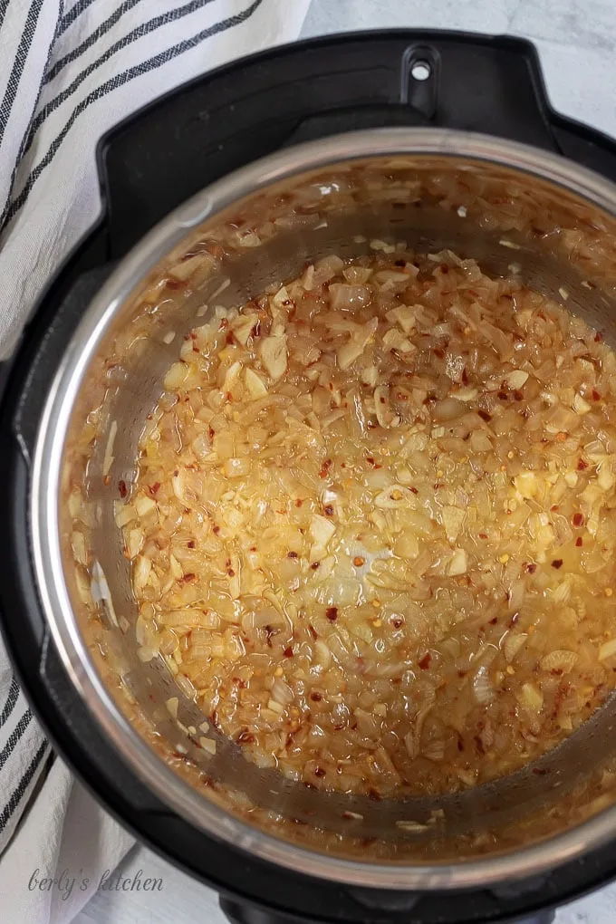Top down view of garlic, onions, salt, and red pepper flakes in the Instant Pot for penne with vodka sauce recipe.