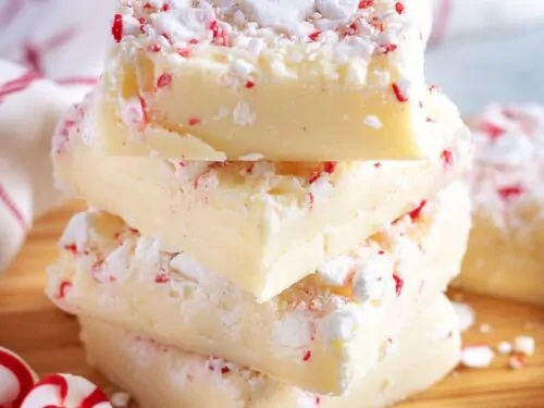 Four pieces of peppermint fudge stacked on a cutting board for presentation.