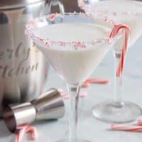 The finished peppermint martinis, rimmed with crushed peppermint candy, and garnished with a candy cane.
