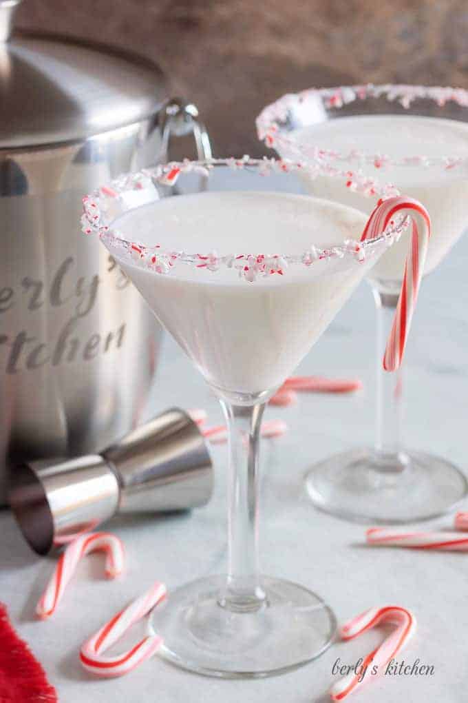 The finished peppermint martinis, rimmed with crushed peppermint candy, and garnished with a candy cane.