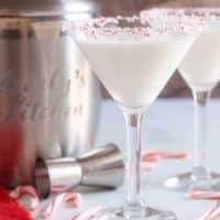 Two peppermint martinis in martini glasses, with a candy cane garnish.