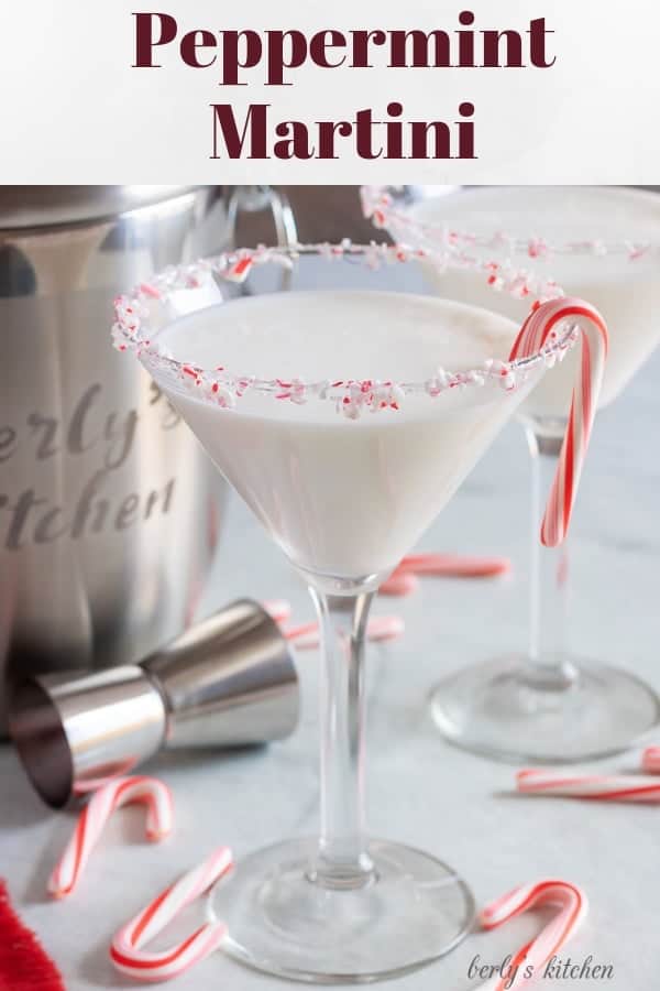 Two finished peppermint martinis with a candy cane garnish, and rimmed with crushed candy canes.