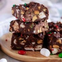 Rocky road fudge stacked on a wooden plate with candies and marshmallows.