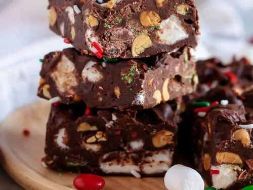 Rocky road fudge stacked on a wooden plate with candies and marshmallows.