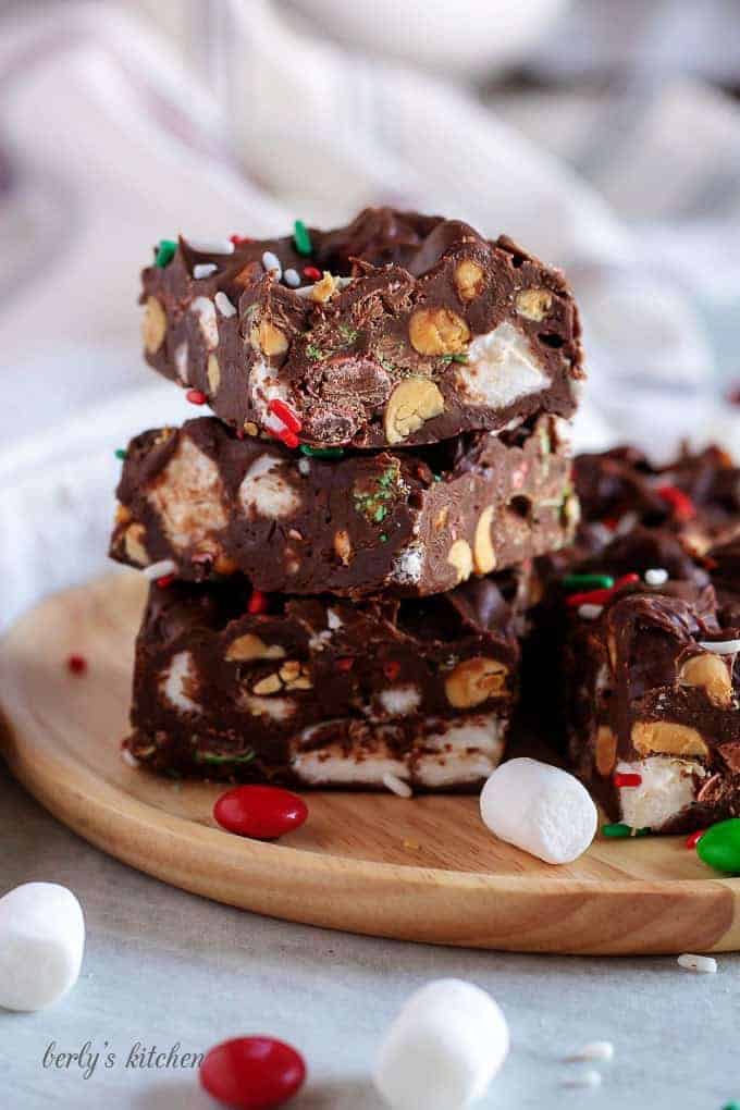 Rocky road fudge stacked on a wooden plate with candies and marshmallows.