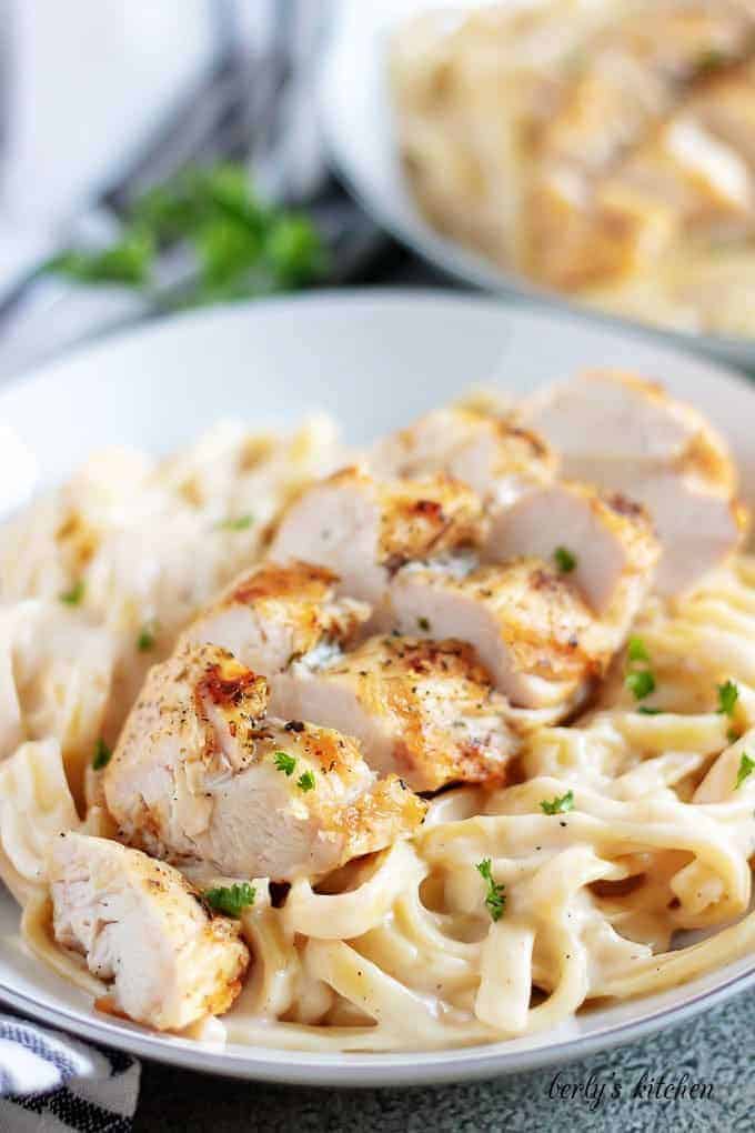 A close-up view of homemade chicken alfredo on a white plate.