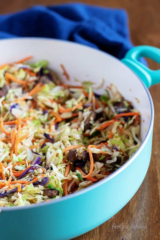 The carrots, mushrooms, and slaw, cooked in a large skillet.