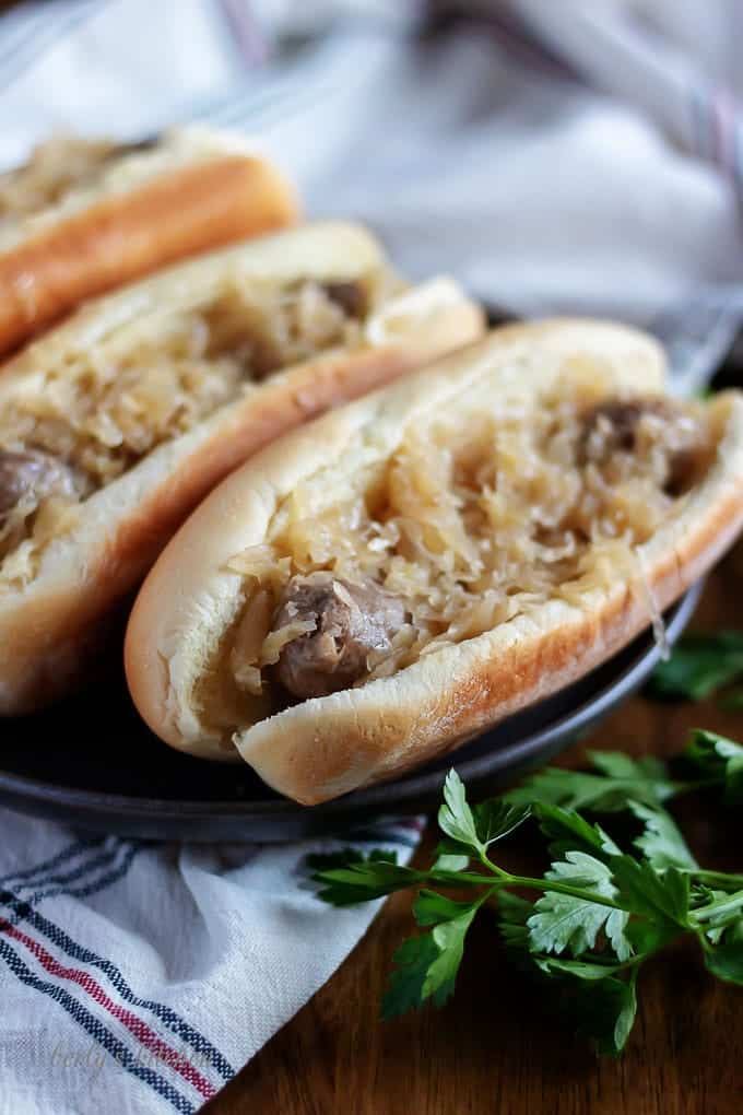 Beer brats, in buns, garnished with extra sauerkraut and sauted onions.