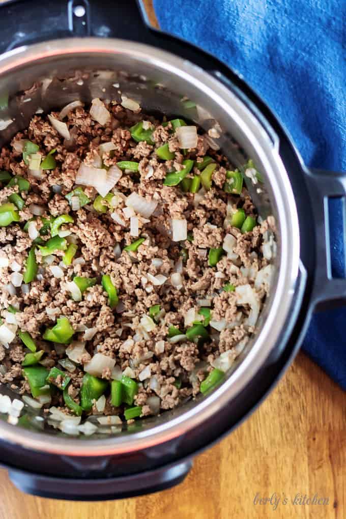 Top-down view of the beef, onions, and peppers in the instant pot.