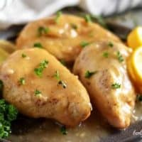 Three lemon chicken breasts, covered in sauce, and garnished with parsley.