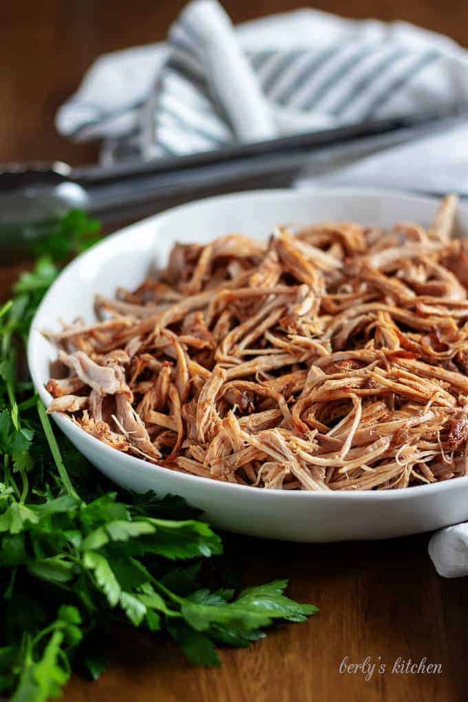 The pulled pork, ready to be served with metal tongs.