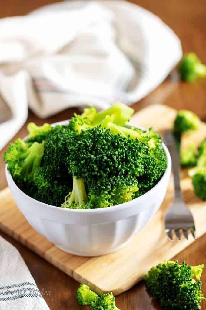 A picture of the instant pot steamed broccoli in a bowl on a cutting board.