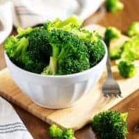 The steamed broccoli in a small white bowl with a fork.