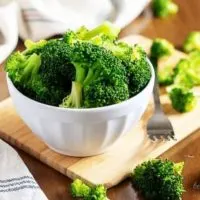 The steamed broccoli in a small white bowl with a fork.