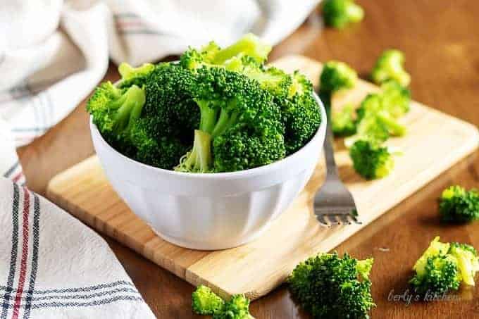 The steamed broccoli in a small white bowl with a fork.