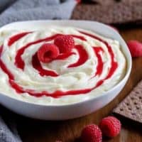 The white chocolate raspberry cheesecake dip topped with sauce and fresh berries.