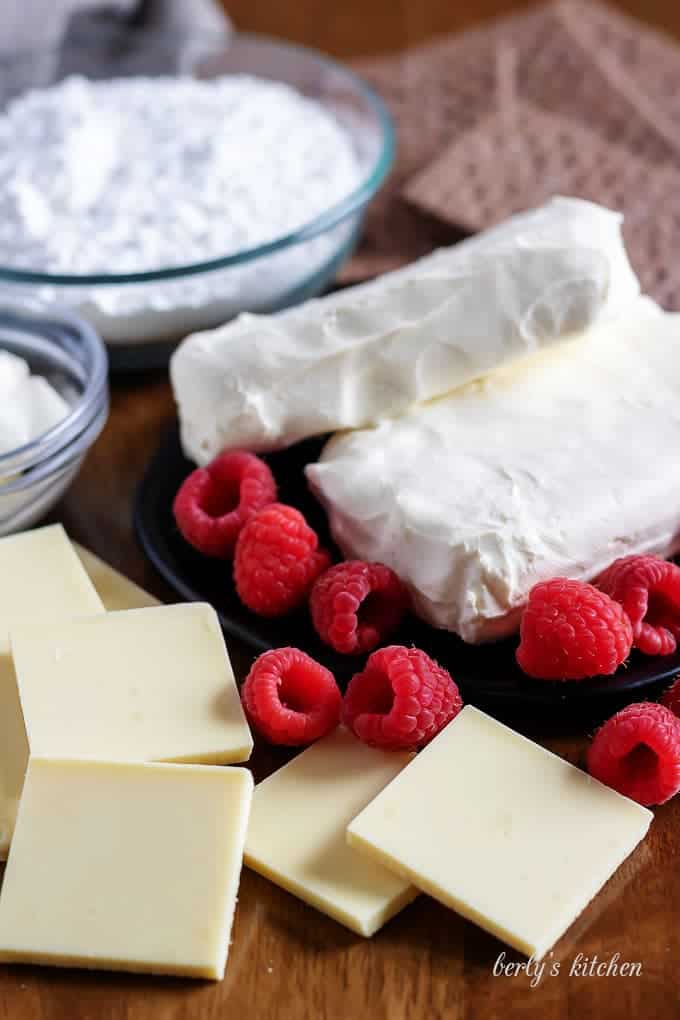 The dip ingredients like sugar, cream cheese, fresh raspberries, and white chocolate.