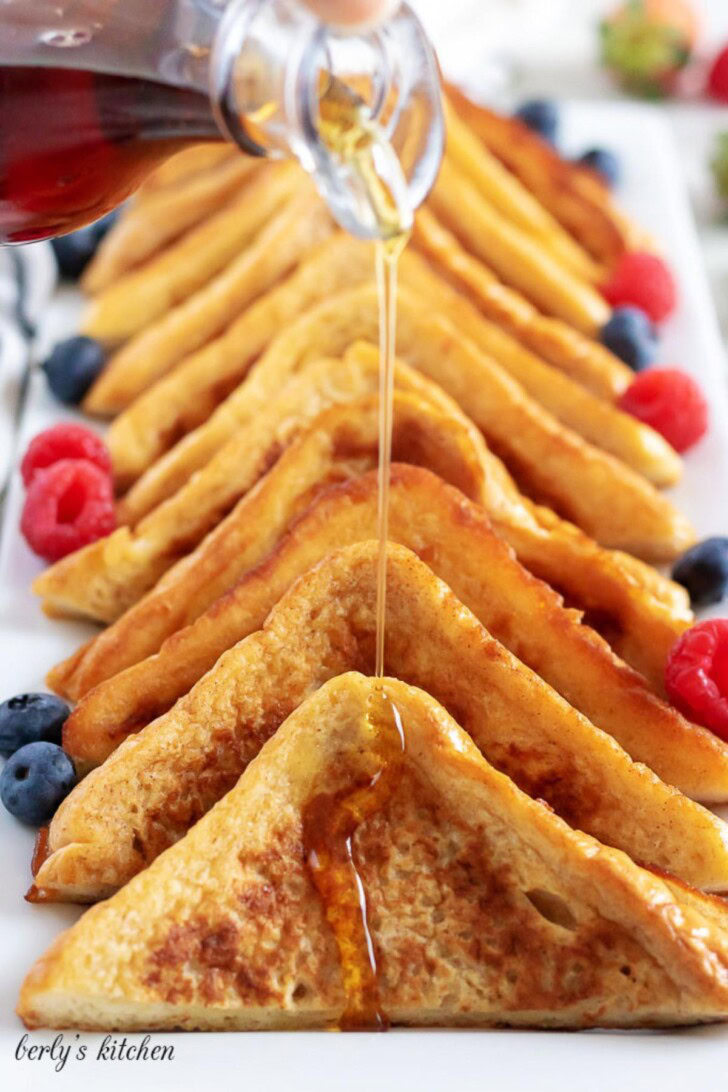Cinnamon French Toast slices lined on a white dish with syrup.
