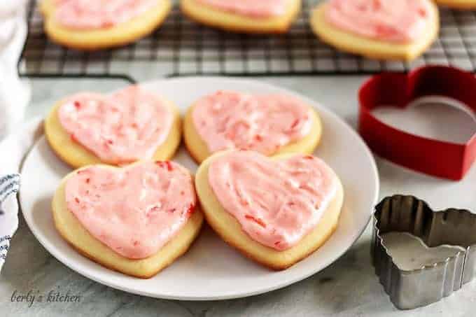 Cut out sugar cookies with cookie cutters on a plate.