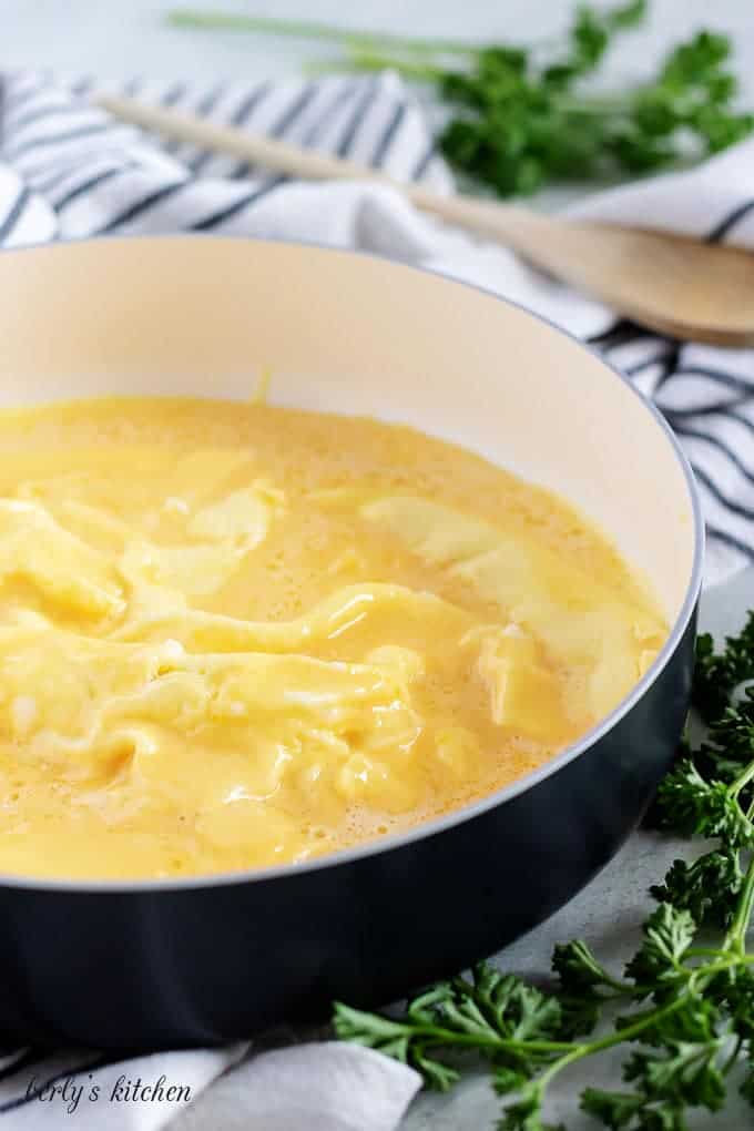 The egg and cream mixture scrambling in a large black skillet..