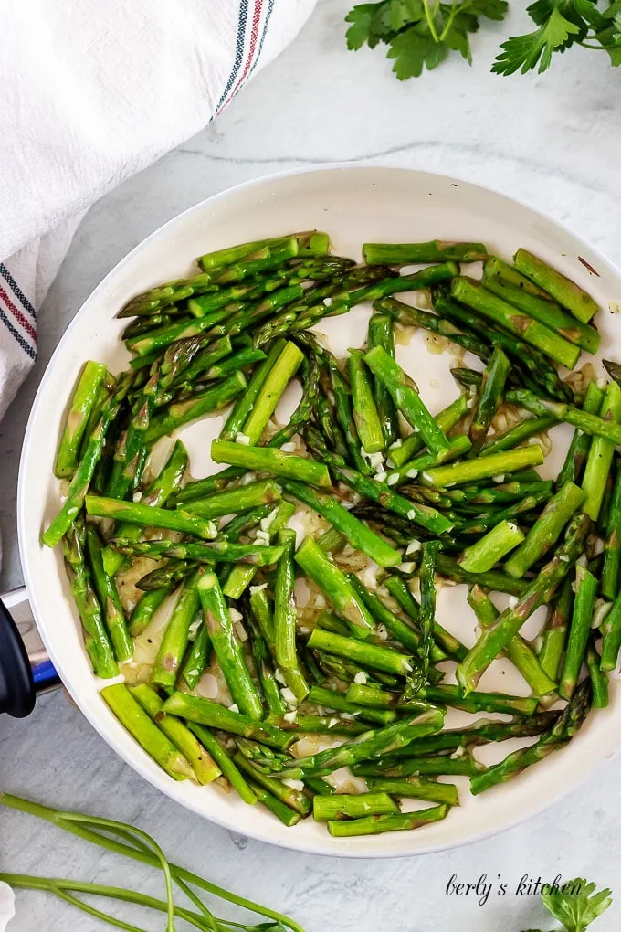 An aerial view of the asparagus and garlic sauteed in a pan.