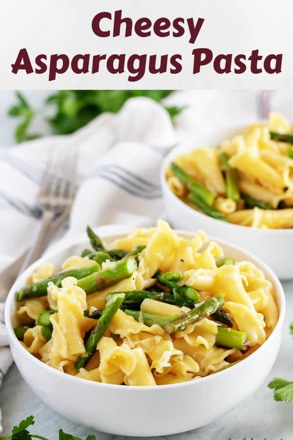 Two white bowls filled with cheesy asparagus pasta and topped with Parmesan.