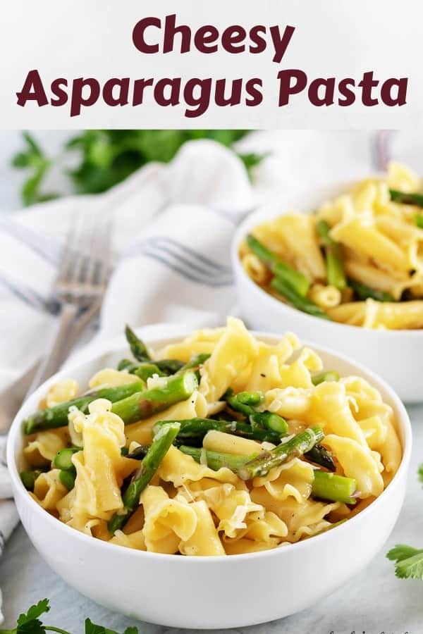 Two white bowls filled with cheesy asparagus pasta and topped with parmesan.