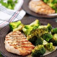 Two plates of grilled pork chops served with the broccoli.