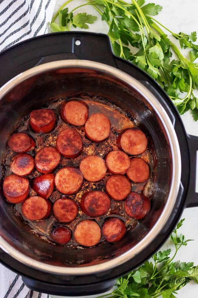 The kielbasa sausage being sauteed in the pressure cooker before sealing.