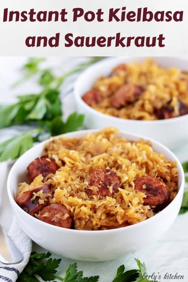 Two bowls, filled with kielbasa and sauerkraut, surrounded by parsley.