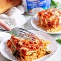 A slice of mushroom lasagna being cut with a fork.