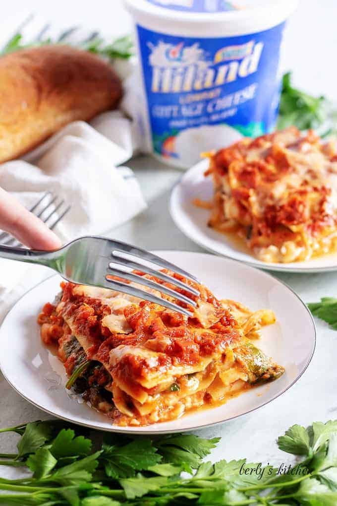 A slice of mushroom lasagna being cut with a fork.