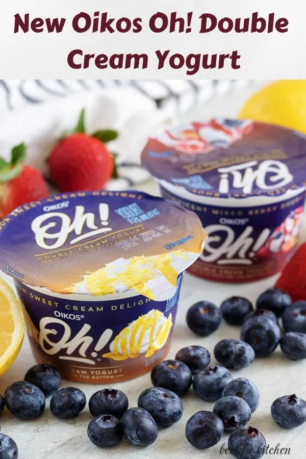 Two unopened packs of Oikos yogurt, surrounded by fresh fruit.